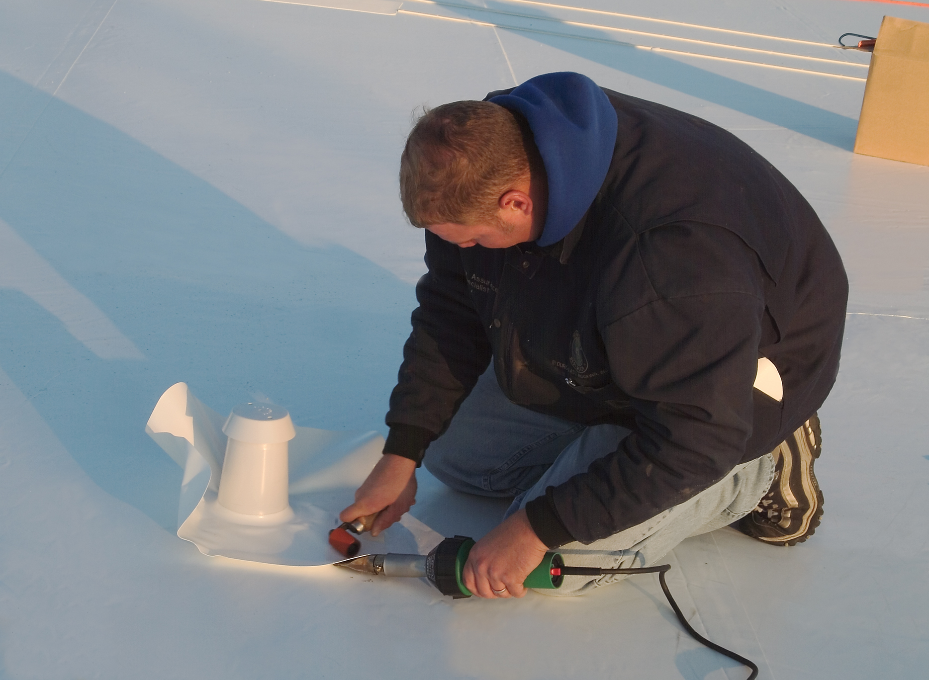 A man installing a single-ply roofing membrane system